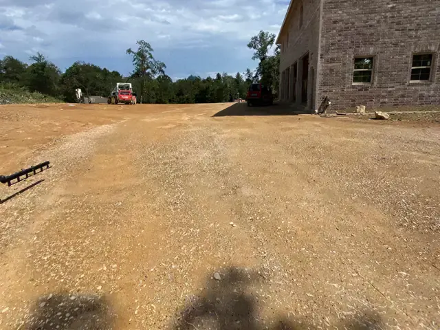 Wide gravel drive beside a brick building under construction